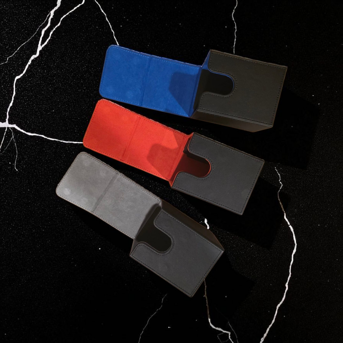 Three wallet cards in different colors - blue, red, and gray - are arranged on a black marble surface.