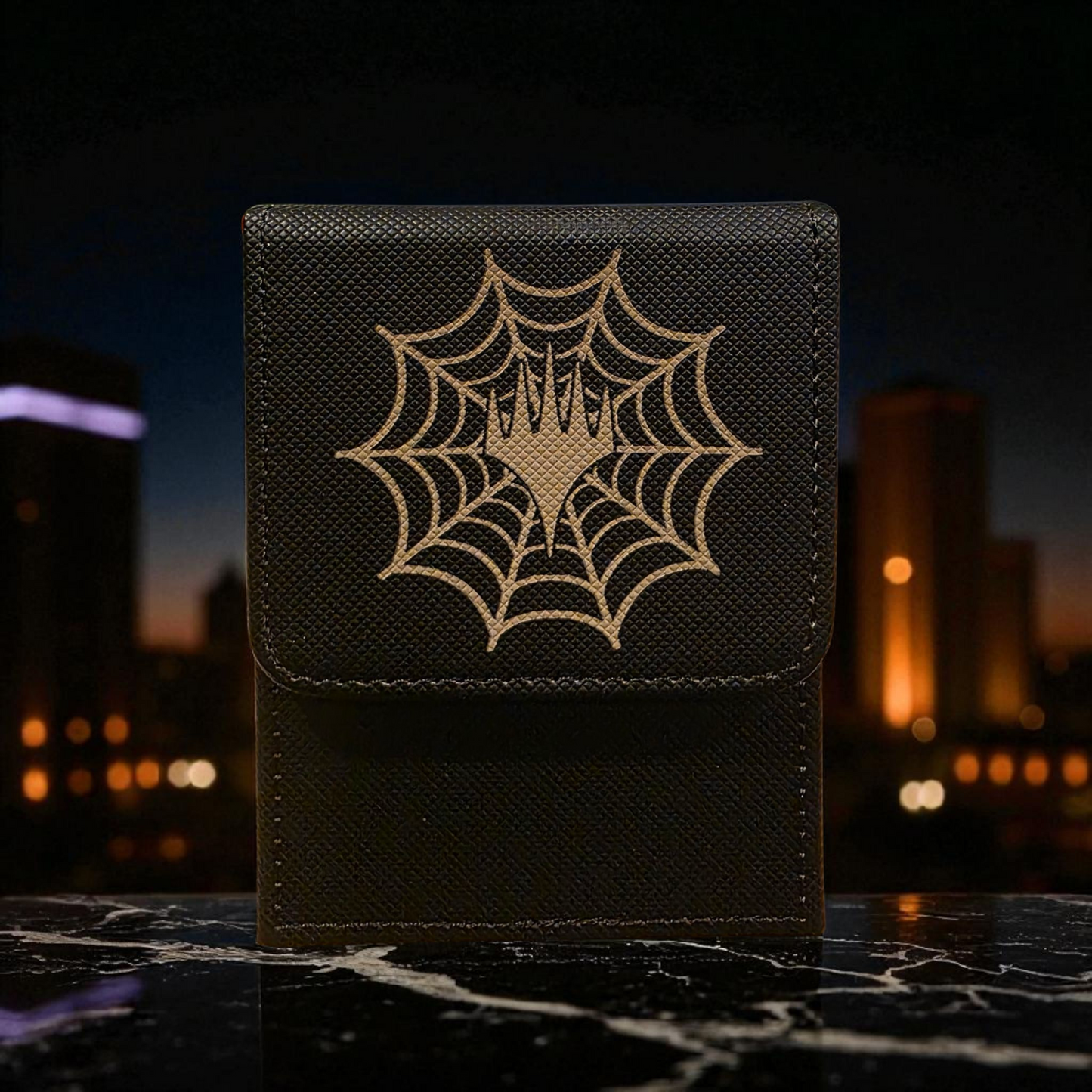 A black leather wallet or card case with a spider web design on it, placed on a marble surface against a blurred cityscape background at night.