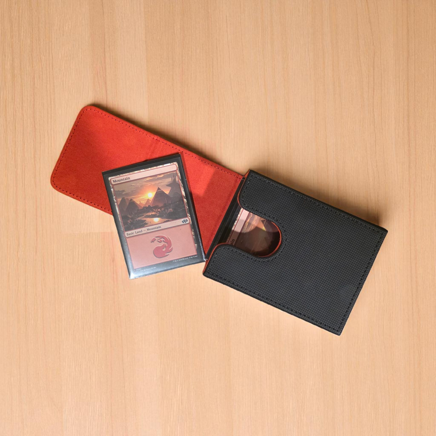 A red and black card case is open, revealing a card inside, placed on a wooden surface.