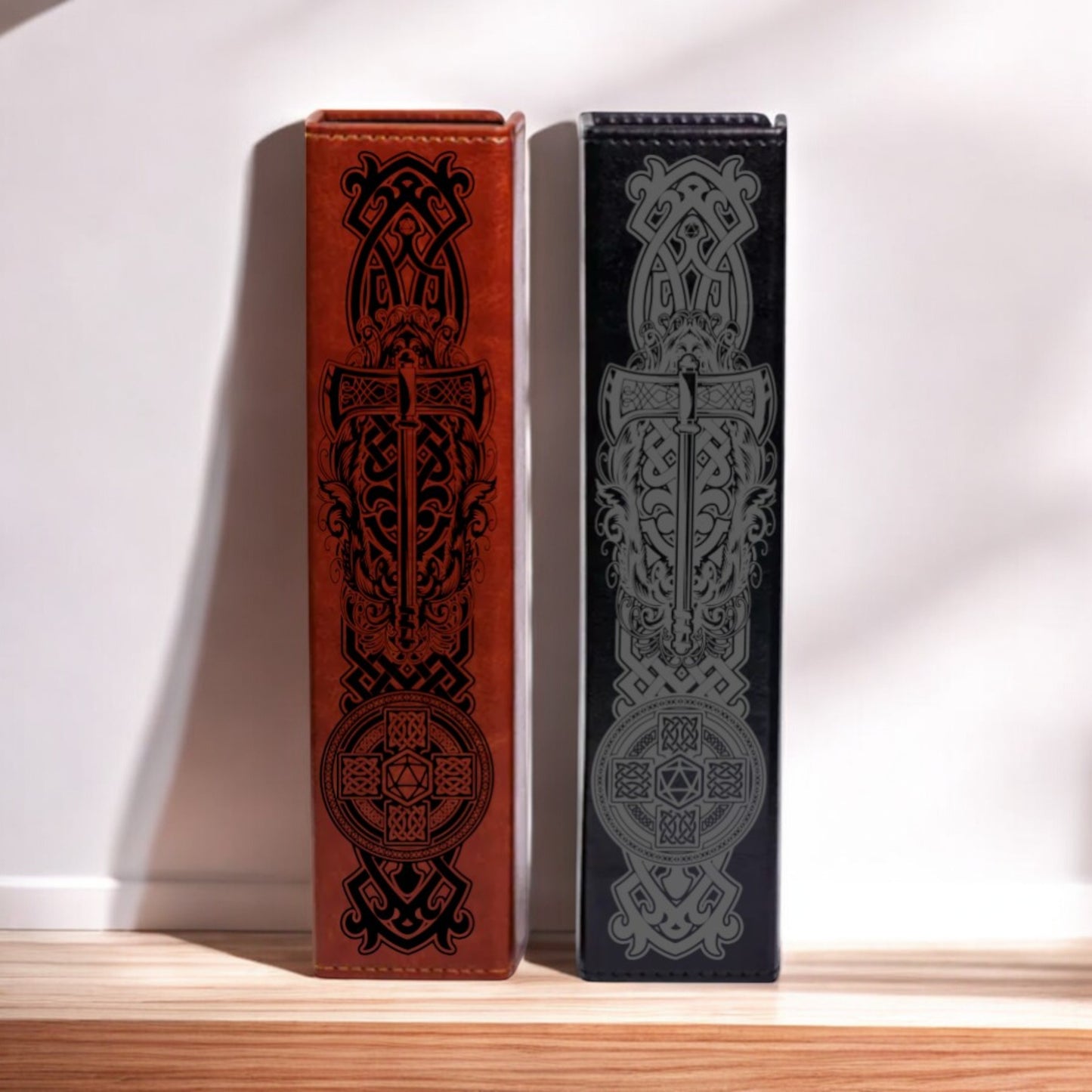 Two ornate leather bookends with intricate black and red designs stand side by side on a wooden shelf against a white wall.