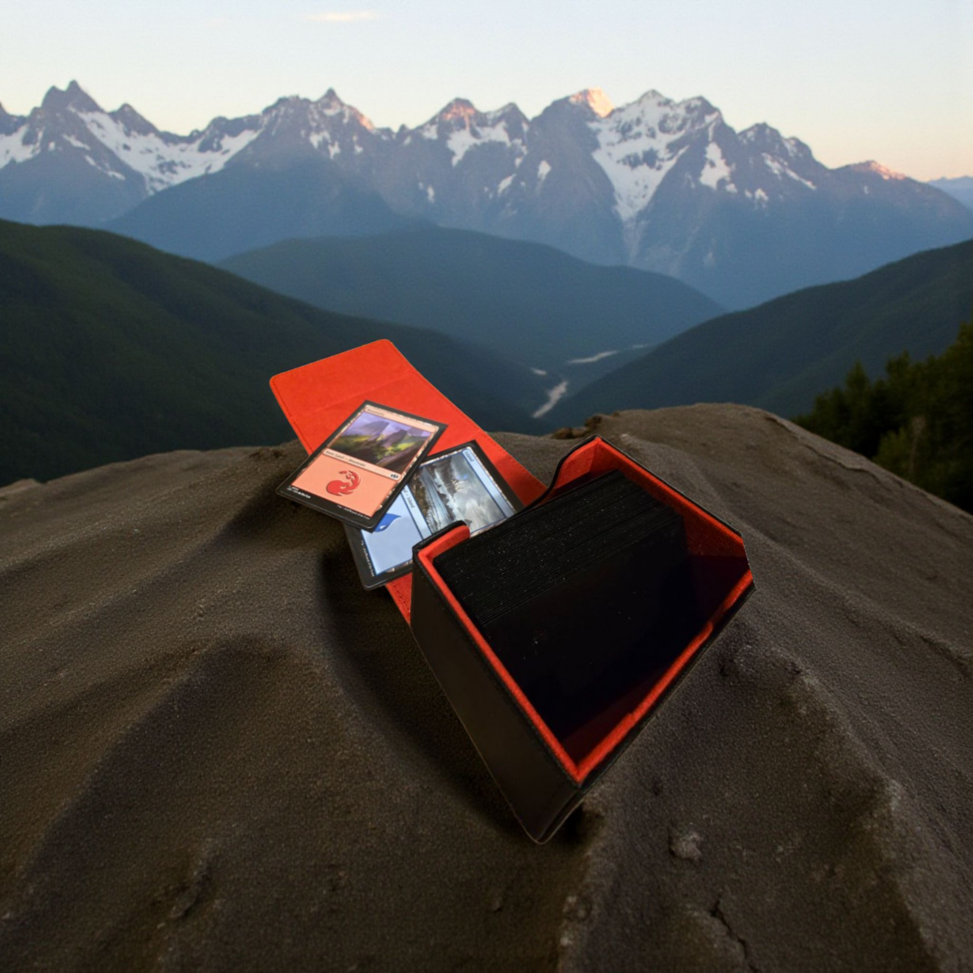 A red and black gaming console is placed on a rocky outcrop, with a mountainous landscape visible in the background.