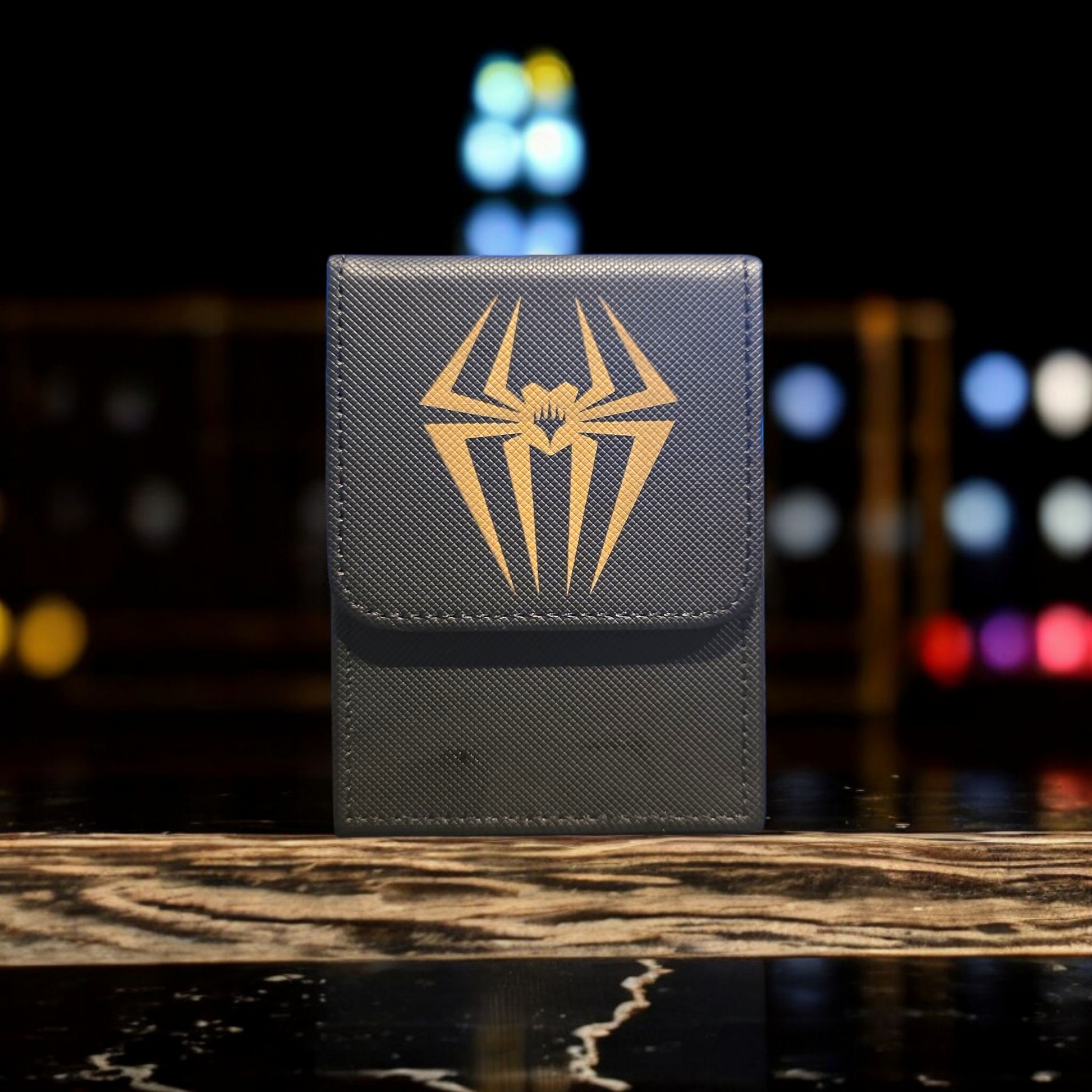 A black wallet with a gold spider logo on it, placed on a marble surface.