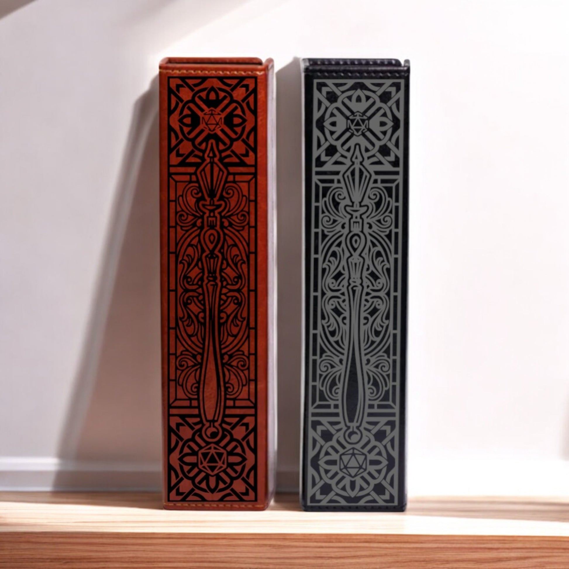 Two ornate, decorative boxes with intricate patterns and designs, one in red and one in black, standing upright on a wooden surface against a white background.
