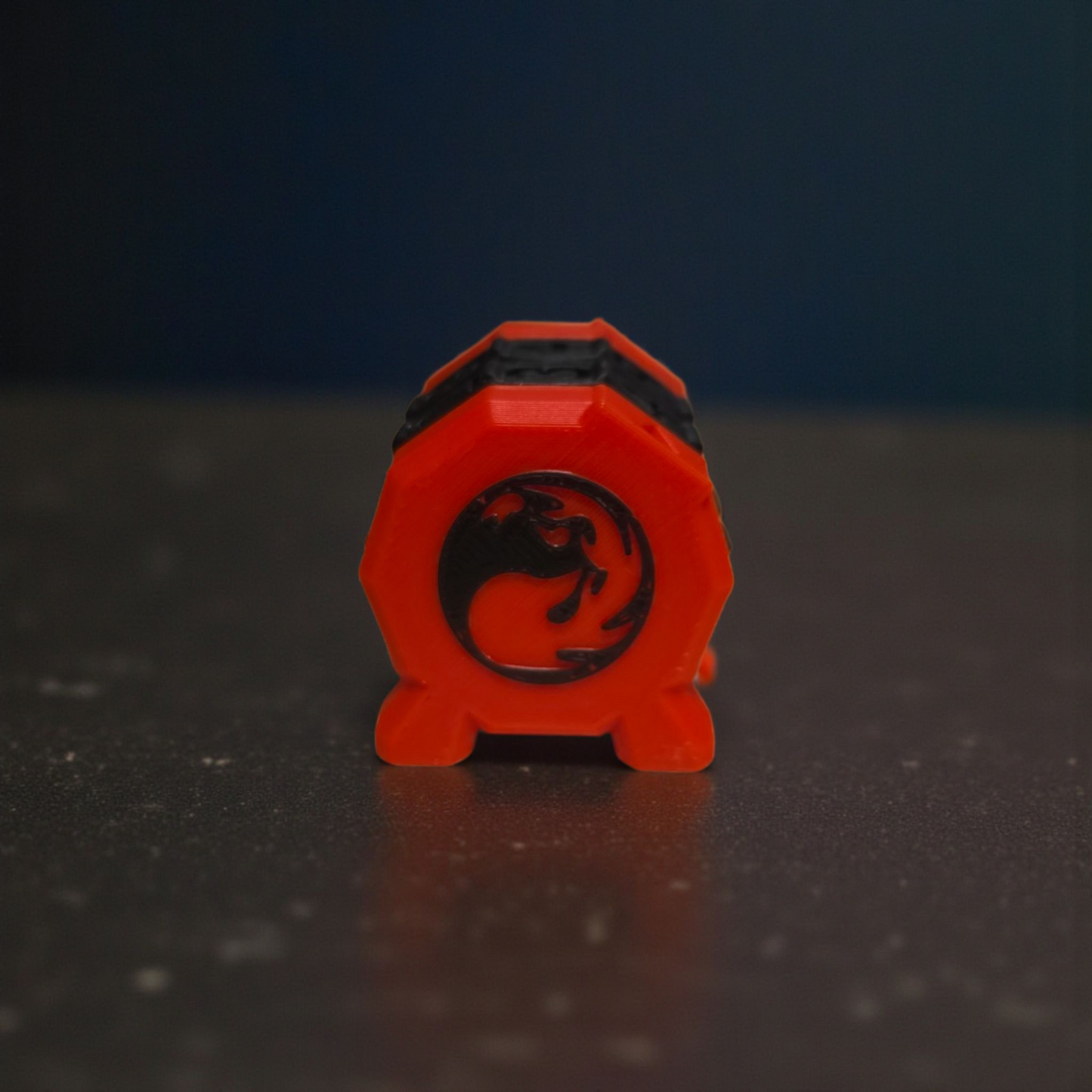 A red octagonal object with a black dragon design on it, sitting on a dark surface.