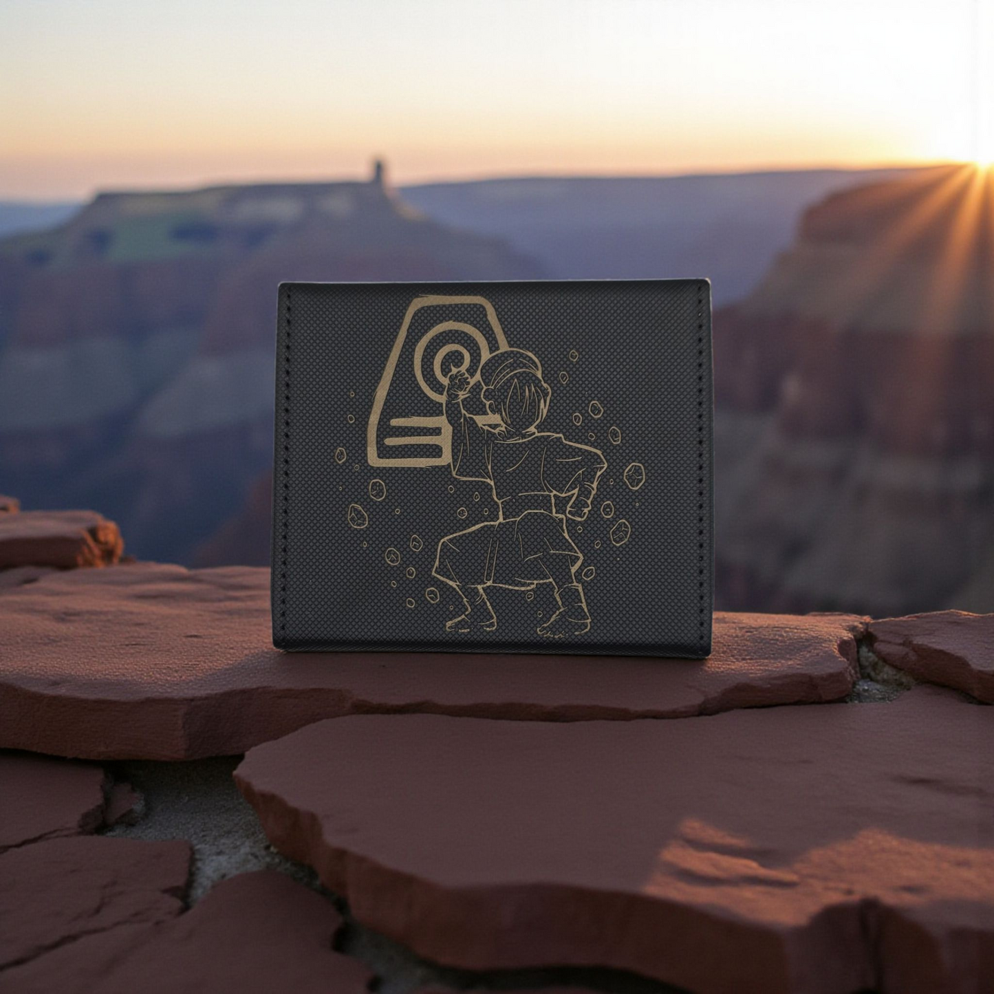 A wallet or card with a design featuring a character from the animated series "Avatar" is placed on a rock formation against a scenic mountain backdrop.