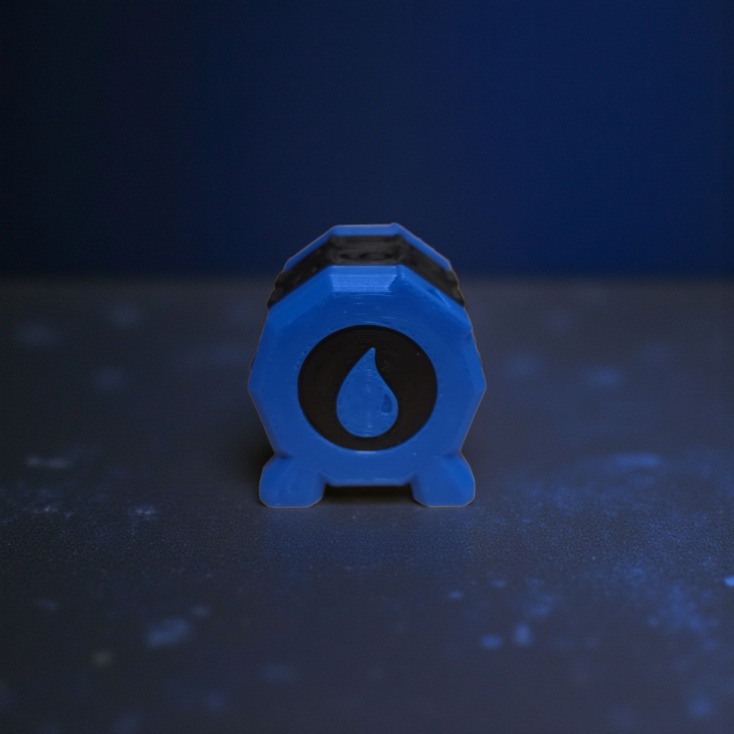 A blue hexagonal object with a black symbol on it, placed on a dark surface.