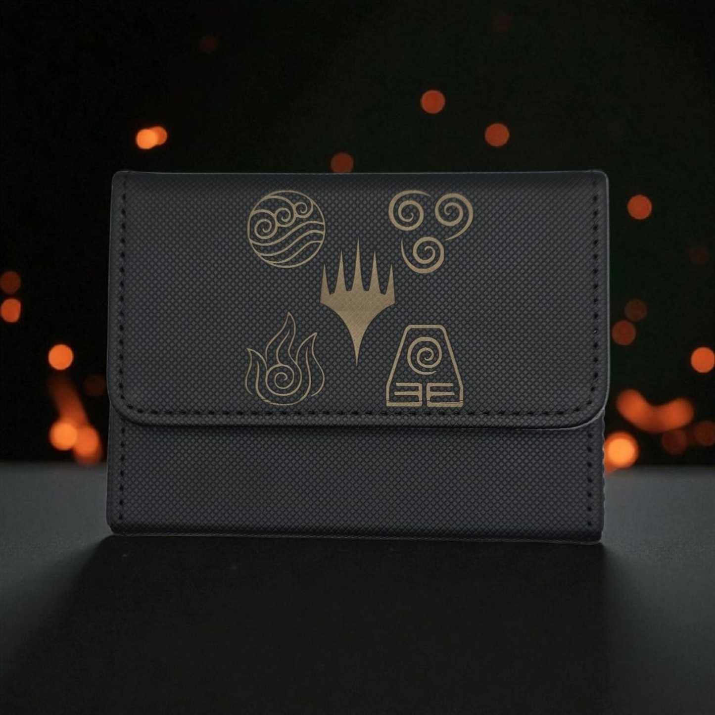 A black wallet or card case with gold symbols and designs on it, placed against a dark background with blurred lights.