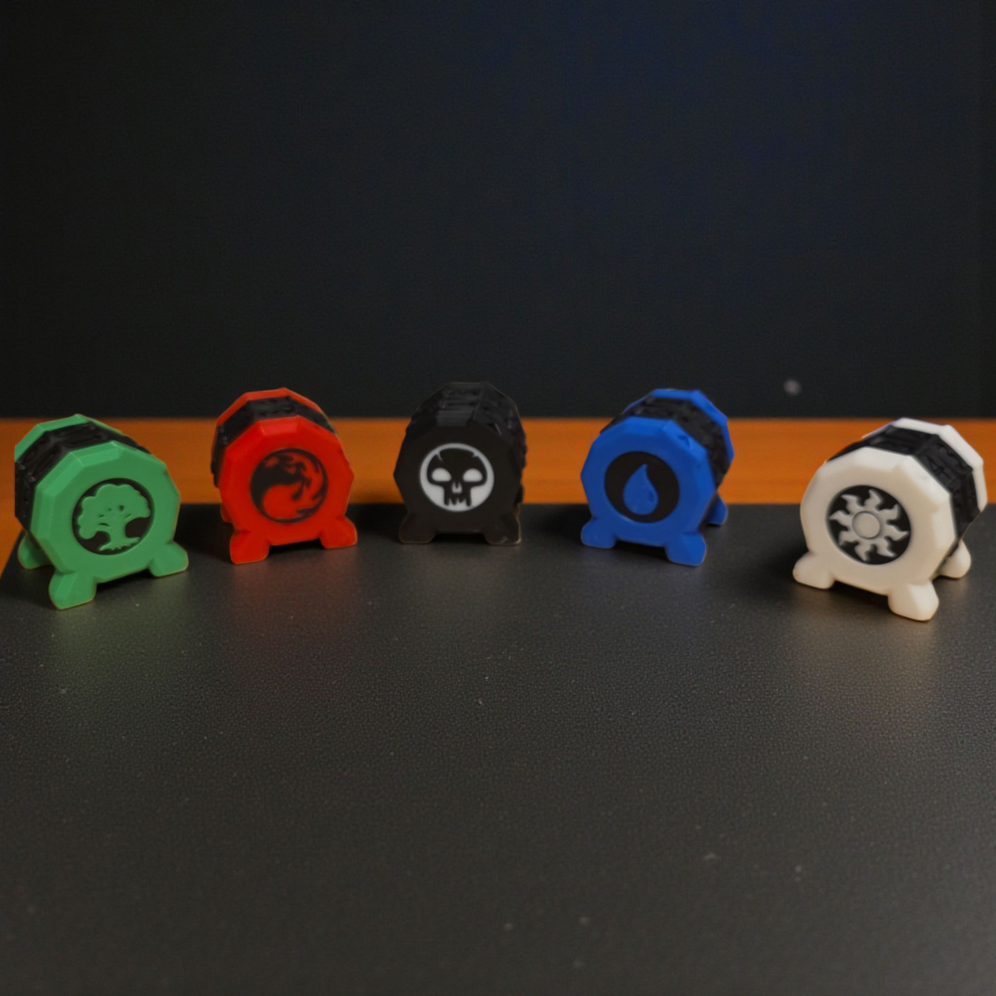 A row of five colorful toy figurines, each with a unique design, are arranged on a dark surface.