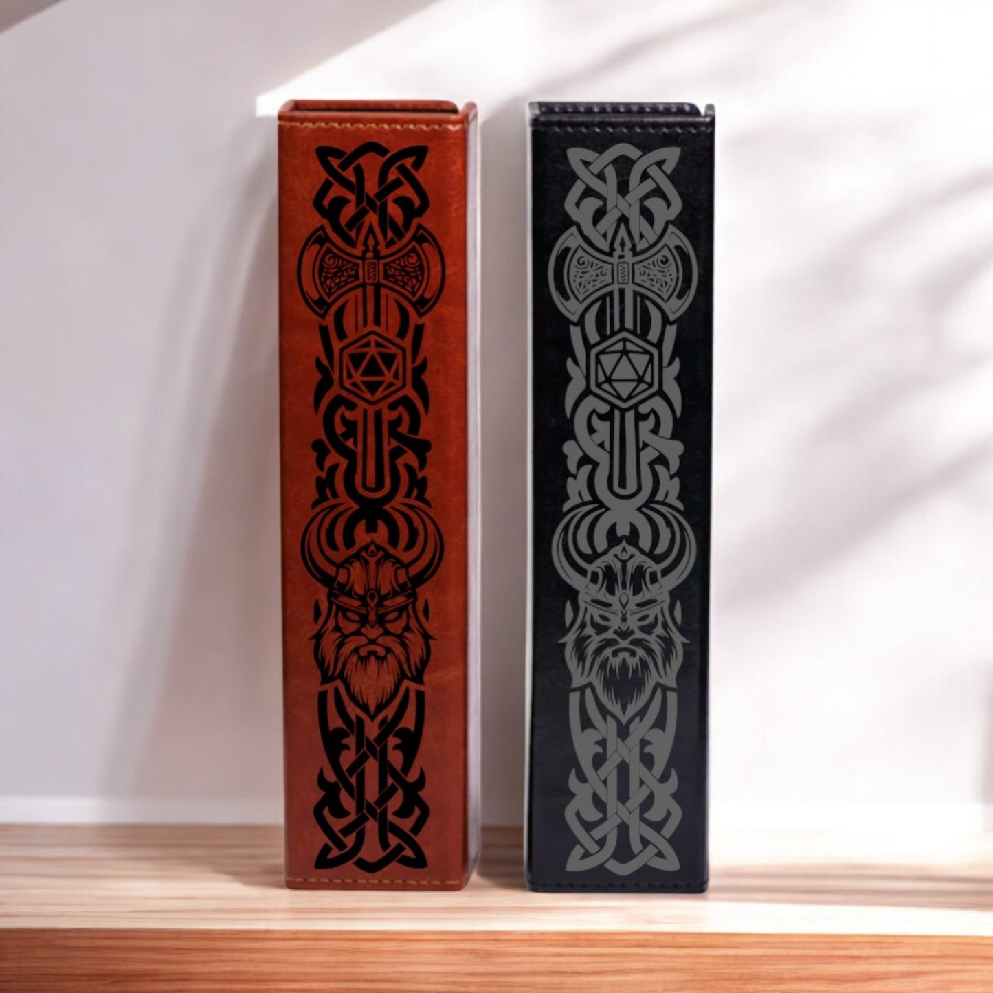 Two leather-bound books with intricate black and red designs on their covers stand side by side on a wooden surface.